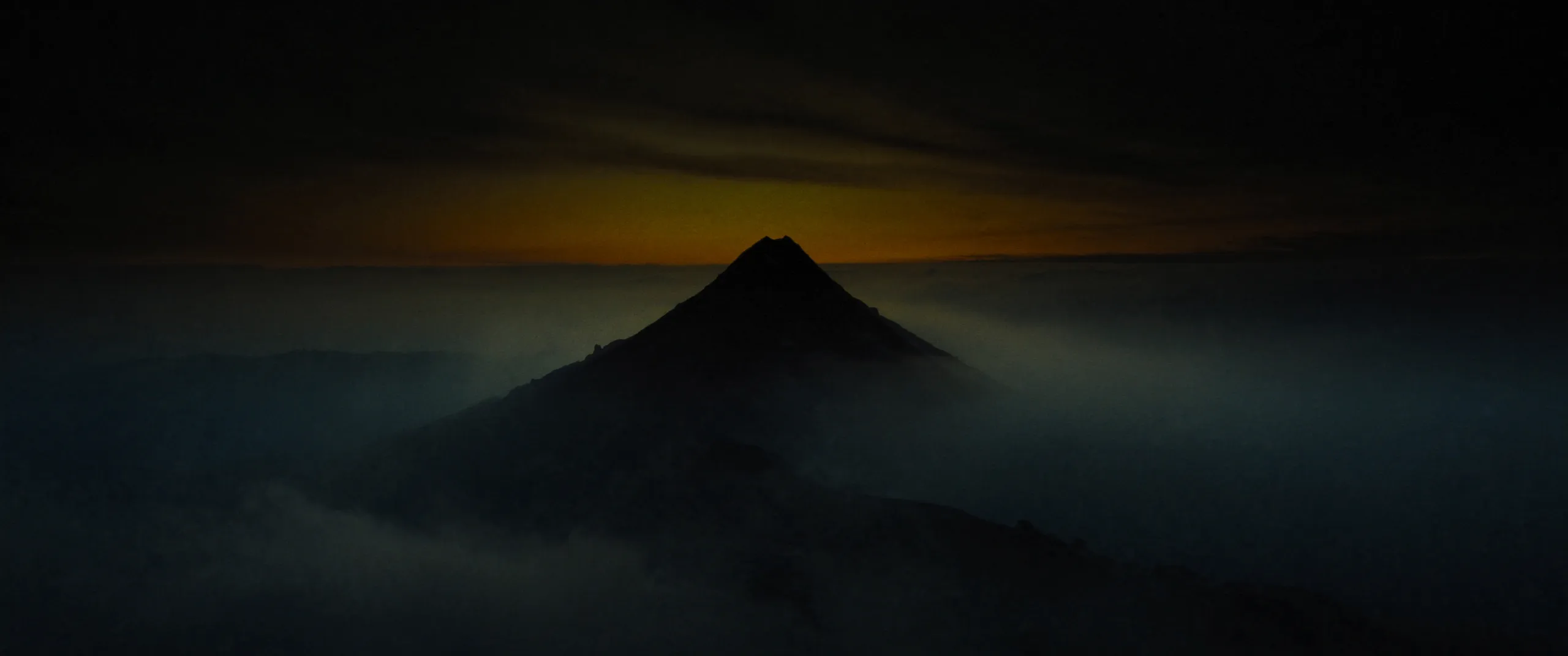 Pico de montanha ao amanhecer, emergindo de um mar de névoa